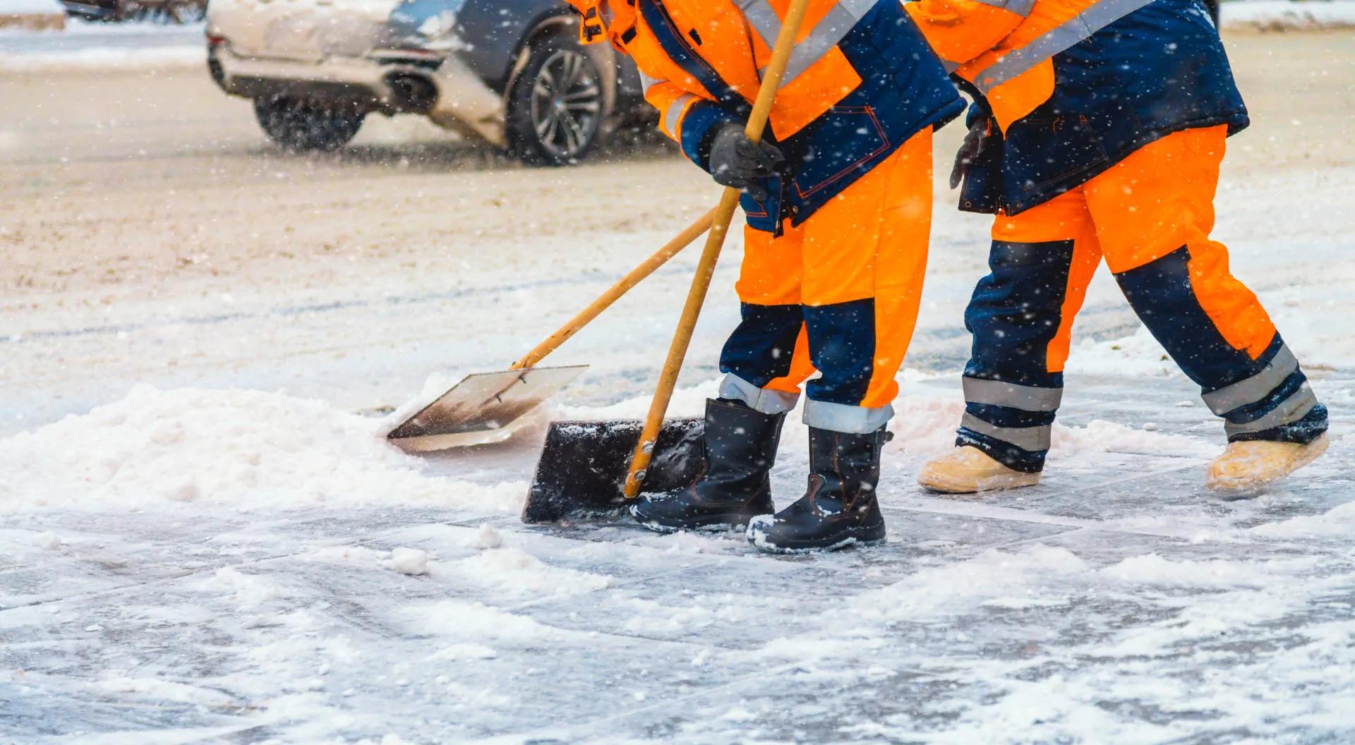 Snow removal crew clearing commercial walkways during storm