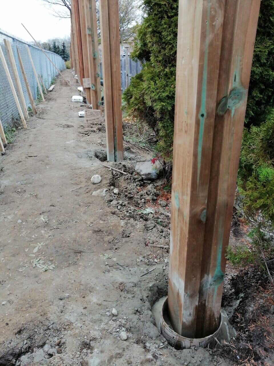 Crew setting pressure-treated fence posts during a wood fence installation in the Greater Toronto Area