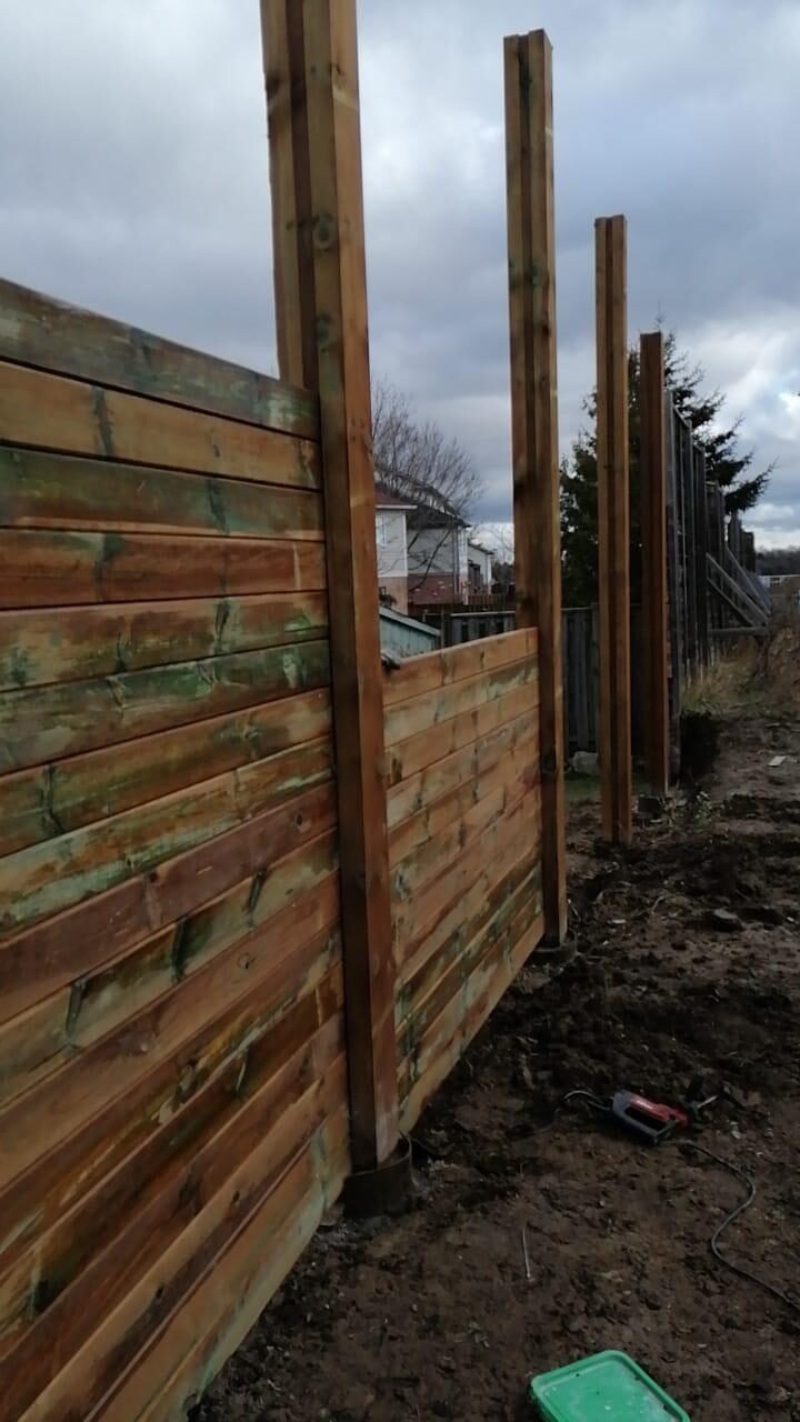 Crew setting pressure-treated fence posts during a wood fence installation in Toronto, ON